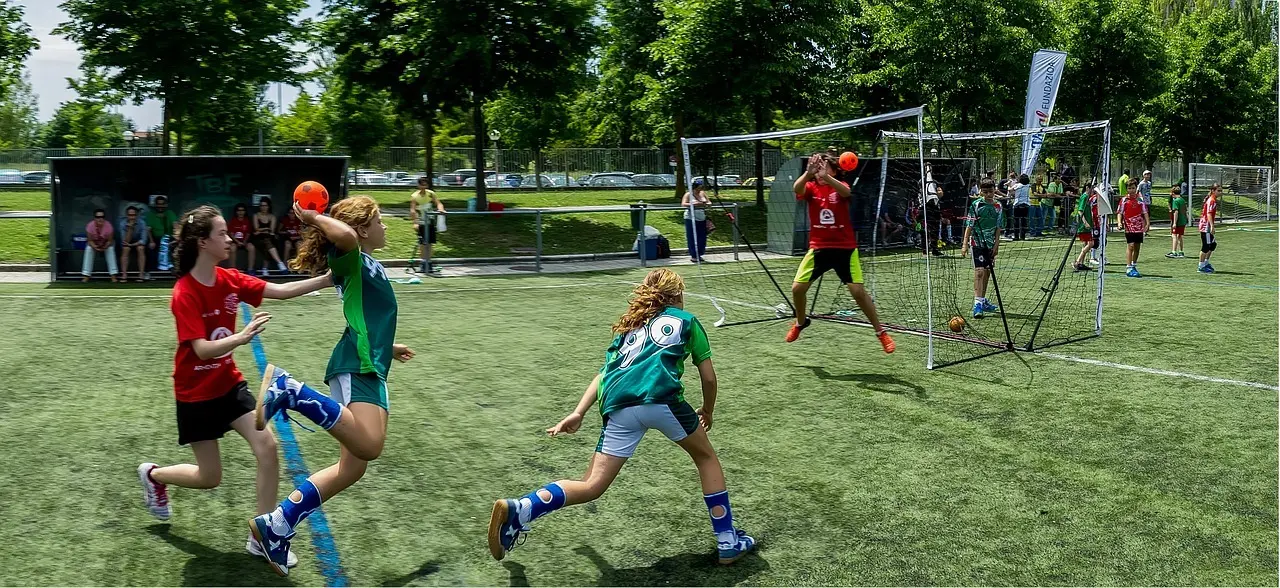 Unge spiller håndbold på kunstgræsbane